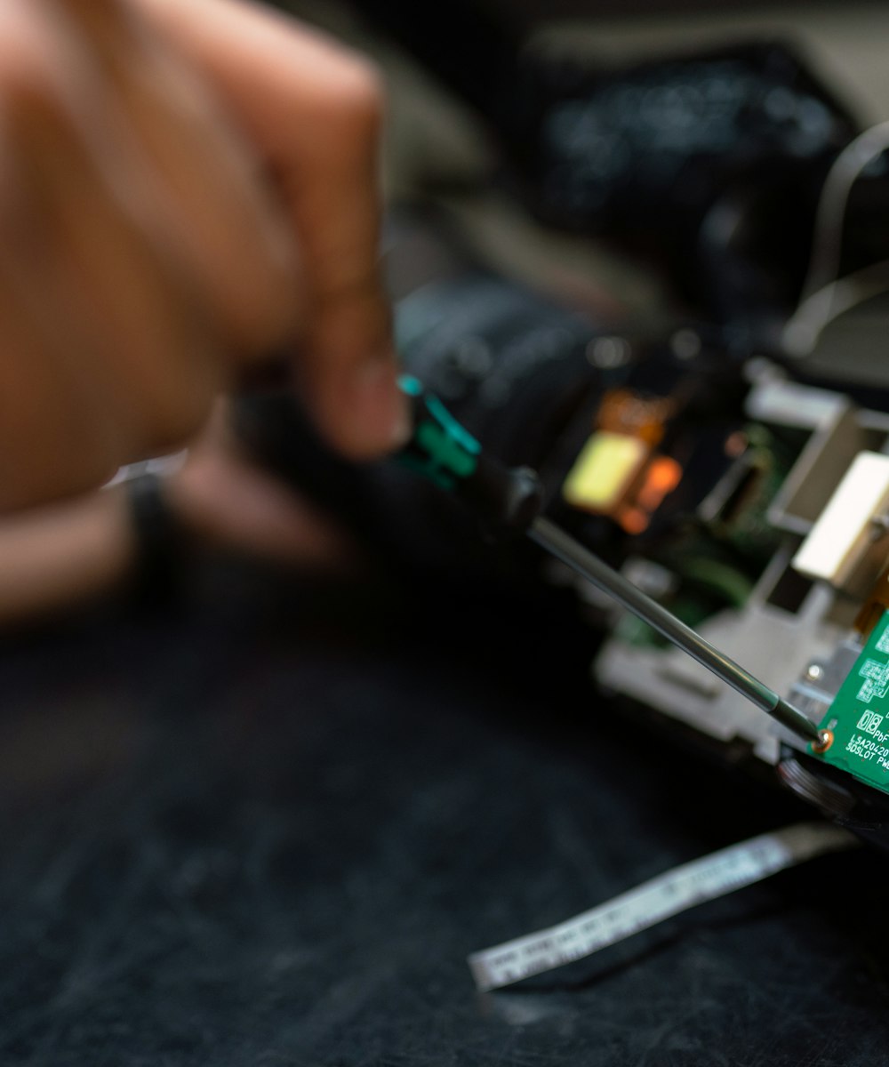 Technician with a screwdriver working on an electronic board